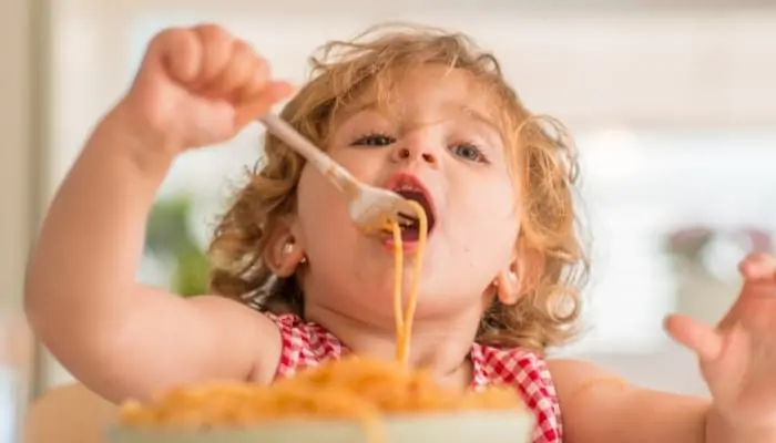 a kid eating spaghetti