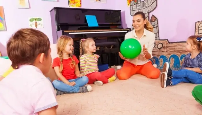 kids sitting in doors in a circle passing the ball