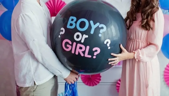 couple holding balloon at gender reveal party