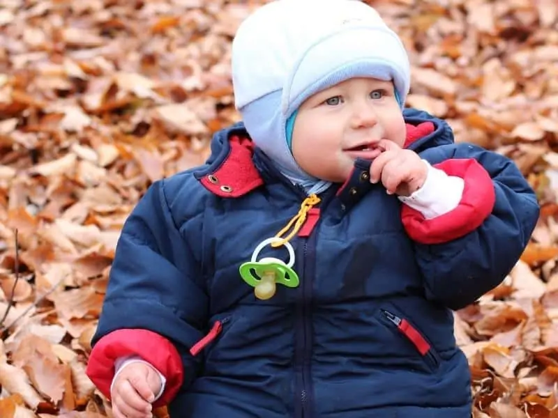 baby sitting on fallen leaves