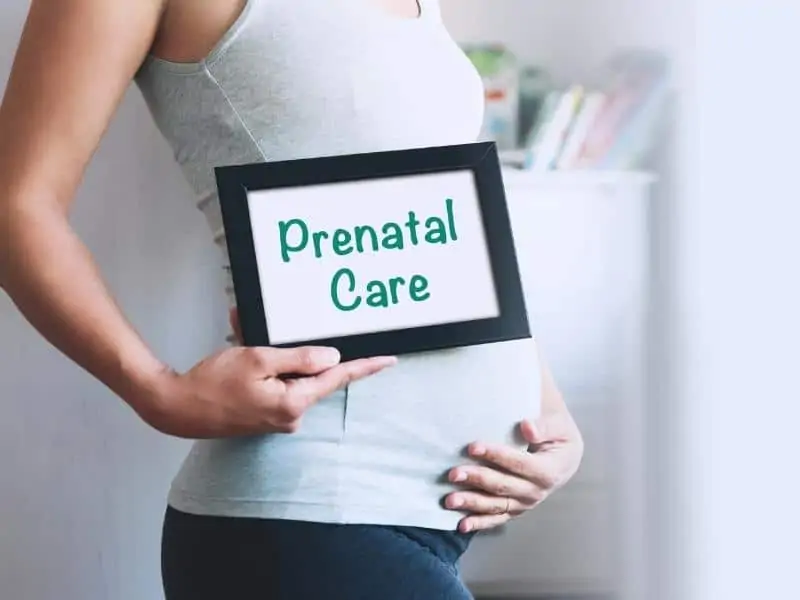 a pregnant woman holding a prenatal care sign