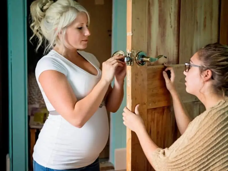 pregnant woman fixing doorknob