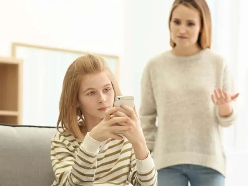 teen with her phone while mom is angry